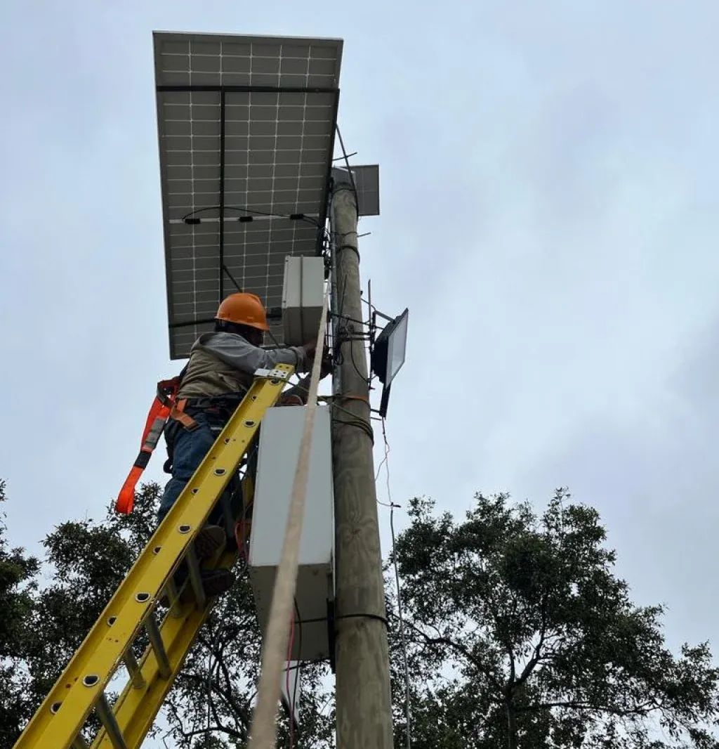 técnico instalando equipos en un poste con panel solar