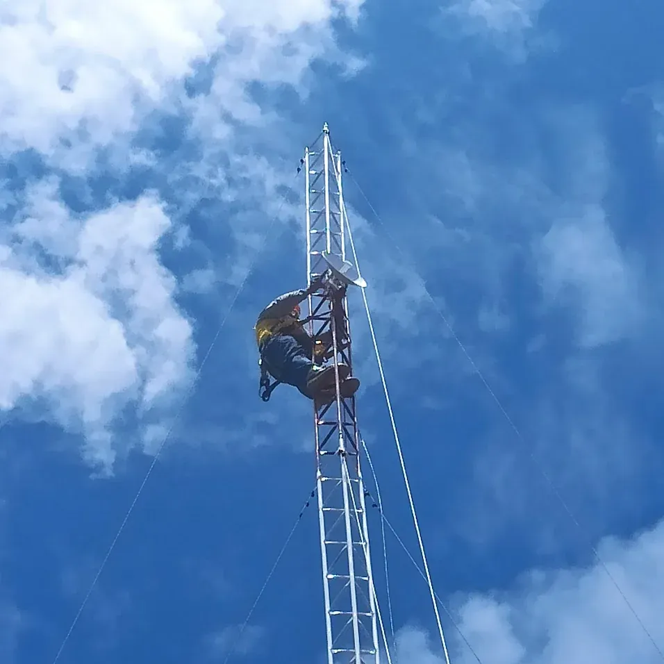 técnico trabajando en lo alto de una torre de comunicaciones